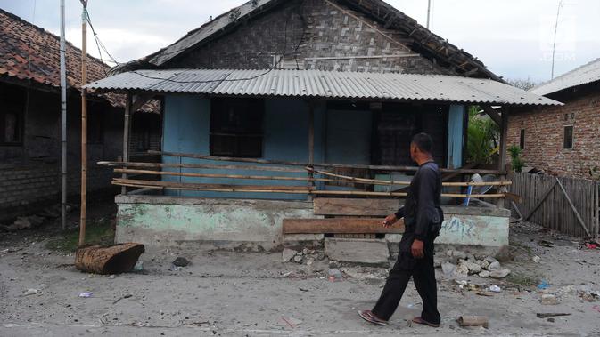 Seorang warga melihat kondisi rumah yang ditinggalkan di dusun Regahan Lada, Pulau Sebesi, Lampung, Senin (31/12). Banyak warga dusun ini yang bertahan di lokasi pascatsunami yang melanda Selat Sunda pada 22 Desember lalu. (Liputan6.com/Herman Zakharia)
