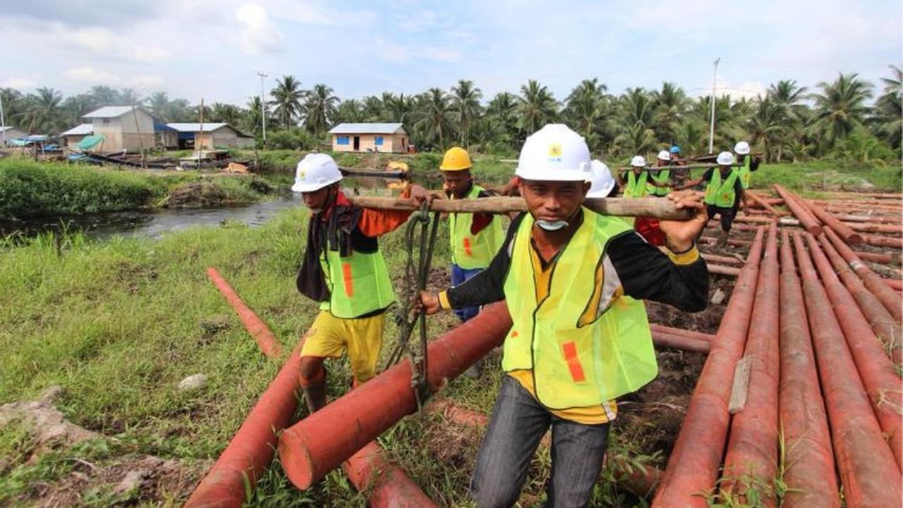 Karyawan PT PLN (Persero) bergotong-rotong mengangkat tiang yang akan digunakan untuk penyangga kabel listrik di Natuna, Kepulauan Riau. (Foto: Humas PLN)