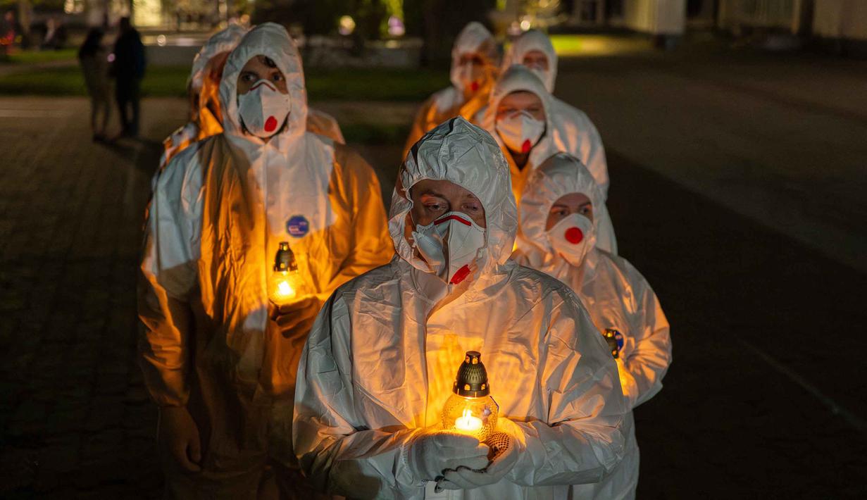 Orang-orang yang mengenakan pakaian pelindung putih membawa lilin selama upacara peringatan yang didedikasikan untuk petugas pemadam kebakaran dan pekerja yang meninggal setelah bencana nuklir Chernobyl, menjelang peringatan 40 tahunnya di Slavutych, Ukraina, Sabtu, 25 April 2026. (AP Photo/Dan Bashakov)