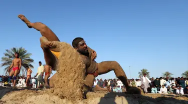 Seorang pegulat Pakistan membanting lawannya saat bertarung dalam kompetisi gulat Greco-Roman mingguan di Dubai (16/3). Mereka melakukan pertandingan gulat gaya kuno. (AFP Photo/Karim Sahib)