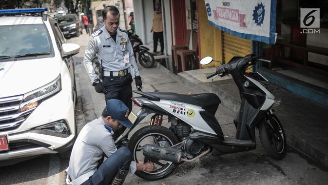 Petugas Dishub DKI Jakarta merazia  kendaraan roda dua dengan mencopot pentil yang terparkir di trotoar di kawasan Cipete Raya, Jakarta, Selasa (13/8/2019). Razia tersebut dilakukan Dishub untuk mengembalikan fungsi trotoar untuk pejalan kaki. (Liputan6.com/Faizal Fanani)