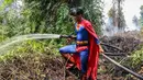 Pelajar bernama Rudiansyah dengan mengenakan kostum Superman membantu memadamkan kebakaran hutan dan lahan di Petuk Katimpun, Palangkaraya, Kalimantan Tengah, 17 Agustus 2026. (AFP/ Reina)