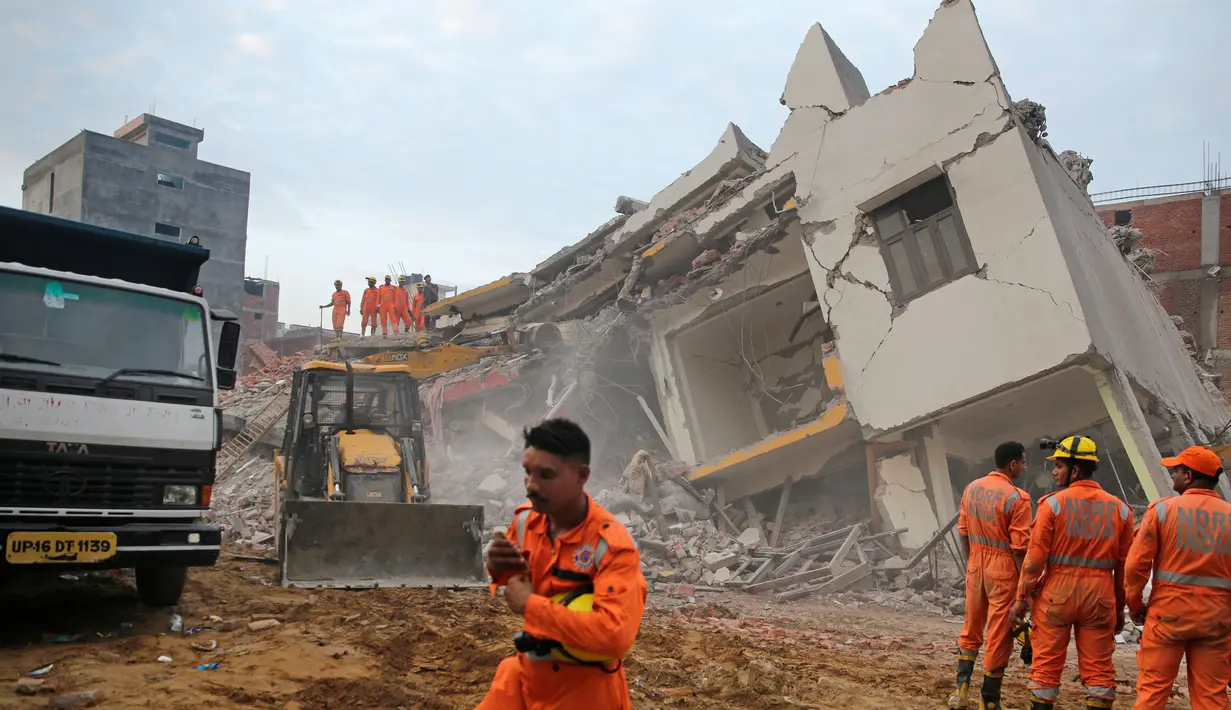 Tim penyelamat berada di lokasi gedung enam lantai yang ambruk di desa Shahberi, pinggiran kota New Delhi, India, Rabu (18/7). Dua orang dilaporkan tewas dan diduga masih ada korban yang terjebak di reruntuhan. (AP Photo/Altaf Qadri)