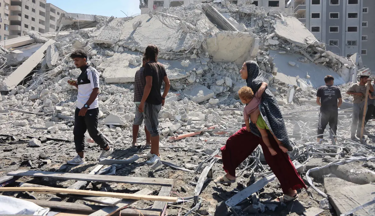 Kantor Media Pemerintah Gaza melaporkan agresi Israel yang kini memasuki hari ke-730 sejak dimulainya perang pada 7 Oktober 2023 telah menyebabkan lebih dari 67.000 warga Palestina gugur dan ratusan ribu lainnya luka-luka. Sementara itu, 90 persen wilayah Gaza nyaris rata dengan tanah akibat serangan udara dan darat Israel. Tampak dalam foto, seorang perempuan Palestina menggendong seorang anak sambil berjalan di antara reruntuhan dekat Menara Tiba yang runtuh beberapa saat setelah serangan Israel menargetkan gedung tinggi tersebut di Kota Gaza pada 10 September 2025. (Omar AL-QATTAA/AFP)