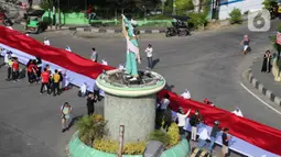 Pelajar SMA membentangkan bendera Merah Putih sepanjang 2,3 kilometer di Jalan Panjaitan dan Jalan Nani Wartabone, Gorontalo, Kamis (23/1/2020). Sebanyak 2.300 pelajar SMA berpartisipasi dalam acara tersebut dengan ikut memegang bendera. (Liputan6.com/Arfandi Ibrahim)