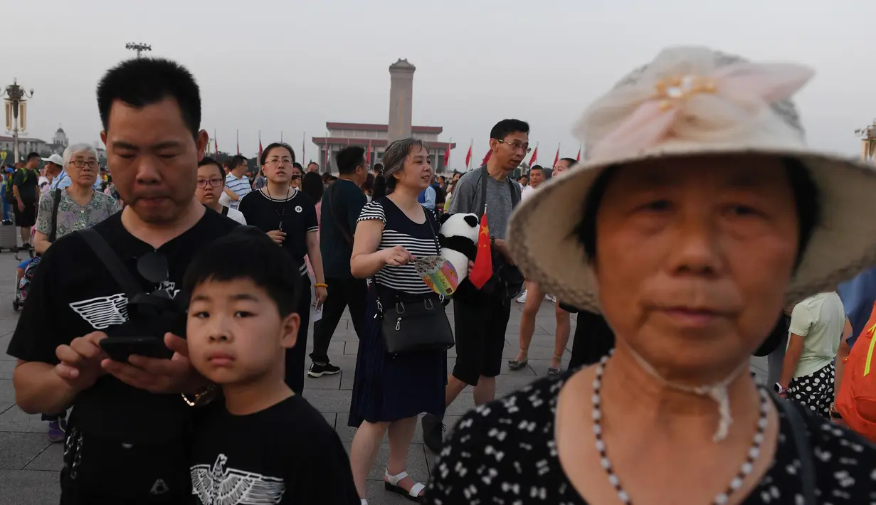 Warga berjalan menghadiri upacara pengibaran bendera saat fajar setelah kematian mantan perdana menteri China Li Peng di Lapangan Tiananmen Beijing (24/7/2019). Li Peng meninggal dunia akibat menderita kanker kandung kemih. (AFP Photo/Greg Baker)