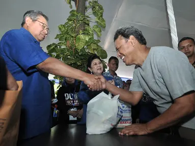 Ketua Dewan Pembina Partai Demokrat Susilo Bambang Yudhoyono atau SBY (kiri) didampingi Ani Yudhoyono (tengah) memberi paket sembako kepada warga saat meresmikan Gerakan Pasar Murah Demokrat di Jakarta, Kamis (7/6). (Liputan6.com/Iqbal Nugroho)