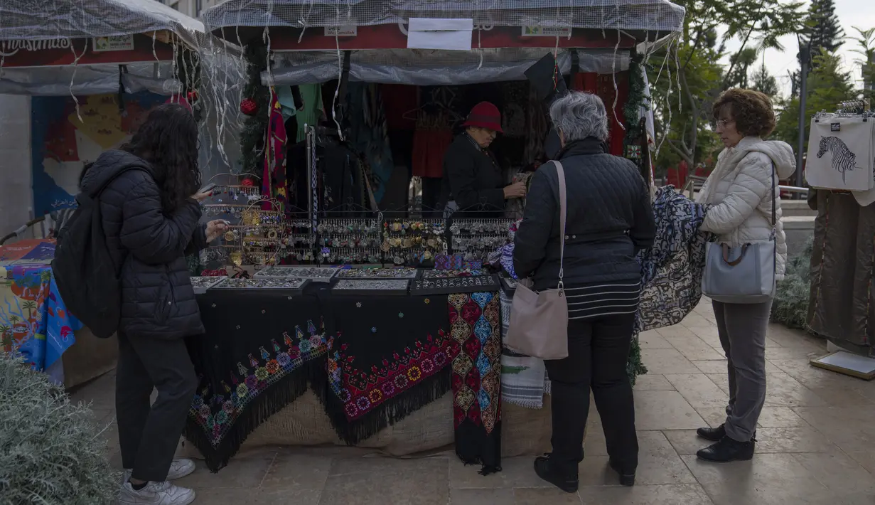Warga Palestina berbelanja oleh-oleh di kios di pasar kerajinan tradisional Natal, di kota Ramallah, Tepi Barat, Rabu, 7 Desember 2022. Warga Palestina memulai musim belanja tradisional Natal sebagai persiapan untuk liburan yang akan datang. (AP Photo/Nasser Nasser)