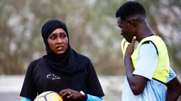 Salma al-Majidi berbincang dengan pemain klub Al-Ahly Al-Gadaref selama latihan di kota Gedaref, timur Khartoum (17/2). Salma tahu cara untuk mengambil bagian dalam olahraga yang dicintainya adalah melatih tim sepak bola pria. (AFP Photo/Ashraf Shazly)