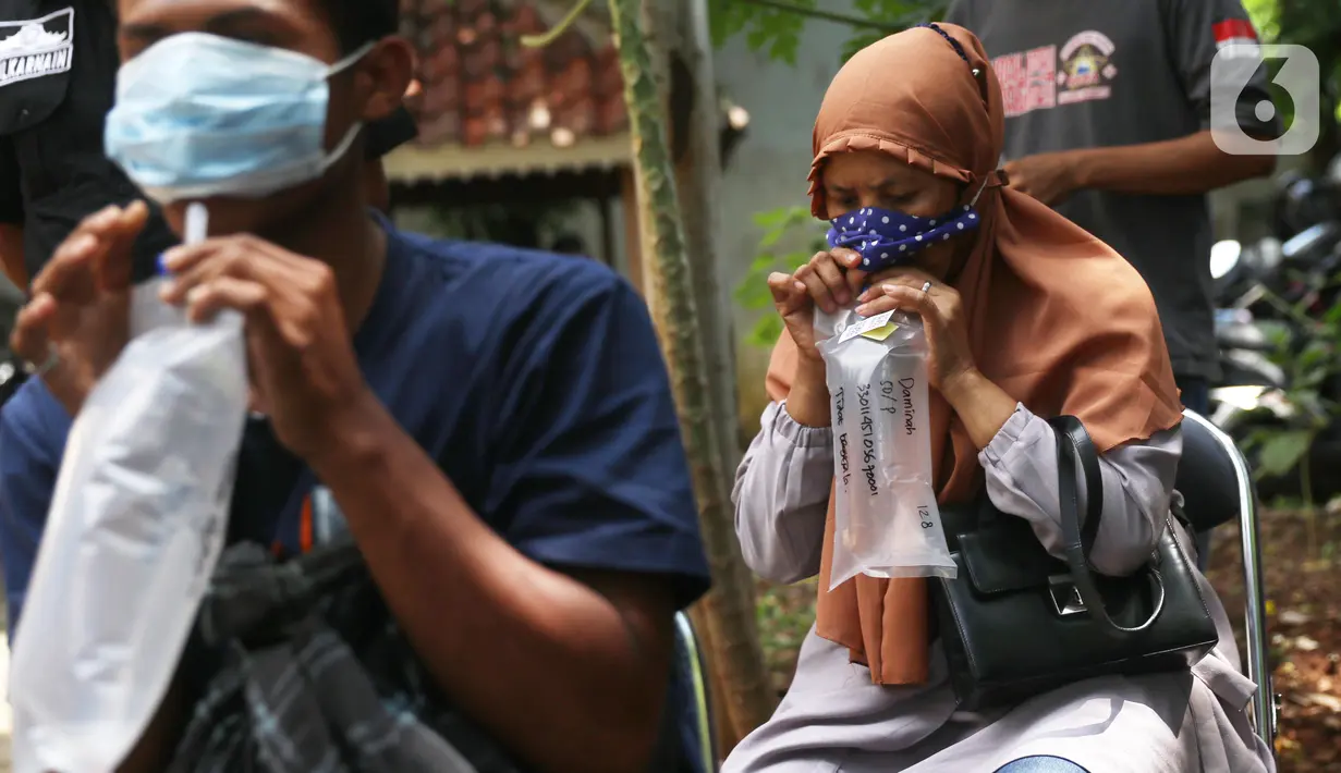 Warga meniupkan kantong saat menjalani tes deteksi COVID-19 dengan metode GeNose C19 usai terjaring razia penggunaan masker di Kelurahan Sudimara Barat, Kota Tangerang, Kamis (27/5/2021). Tes tersebut untuk menekan penyebaran corona di wilayah tersebut. (Liputan6.com/Angga Yuniar)