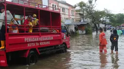 Warga menaiki mobil milik pemadam kebakaran Kota Tangerang untuk melintasi genangan air ketika banjir merendam Jalan KH. Hasyim Ashari, Tangerang, Banten, Sabtu (16/7/2022). Akibat luapan kali angke ruas jalan yang menghubungkan Tangerang-Jakarta itu terputus akibat banjir. (Liputan6.com/Angga Yuniar)