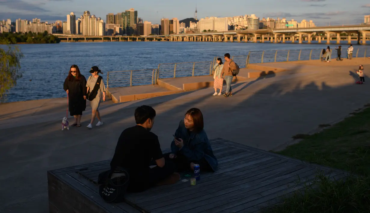 Orang-orang berjalan di sepanjang sungai Han dengan pemandangan cakrawala Seoul di taman Yeouido, Rabu (26/9). Korea Selatan sedang menikmati hari terakhir dari liburan Chuseok atau Hari Thanksgiving. (AFP PHOTO / Ed JONES)