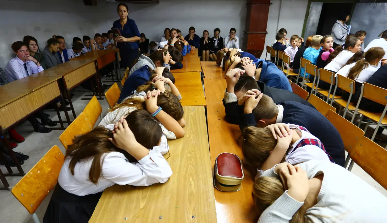 Anak-anak menutupi kepala dengan kedua tangan ketika latihan keamanan di Sekolah Nomor 8, Desa Sartana wilayah timur Ukraina, 2 Oktober 2018. Mereka mempraktikkan yang harus dilakukan jika sekolah mereka menjadi target serangan. (Aleksey FILIPPOV/AFP)