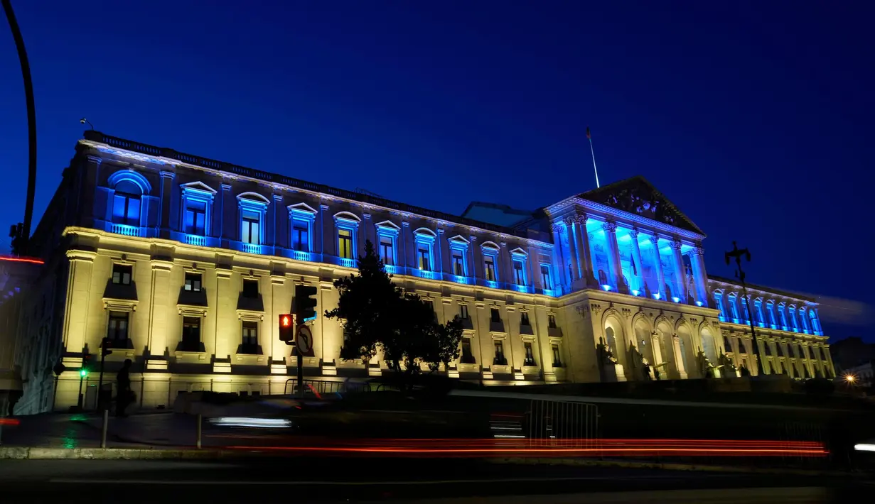 Kendaraan melaju melewati Parlemen Portugal yang diterangi dengan warna bendera Ukraina untuk menandai peringatan satu tahun invasi Ukraina, di Lisbon, saat malam tiba, Kamis, 23 Februari 2023. Menurut Kantor Komisaris Tinggi PBB untuk Hak Asasi Manusia (OHCHR) per 21 Februari 2023, sedikitnya 8.006 jiwa tewas, sementara 13.287 orang terluka sejak invasi Rusia ke Ukraina pada 24 Februari 2022. (AP Photo/Armando Franca)