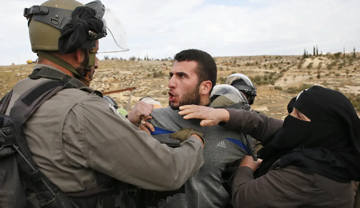 Seorang pria Palestina terlibat bentrok dengan polisi Israel saat memprotes pembongkaran rumah di Desa Al-Dirat, dekat kota Hebron, Tepi Barat (16/1/2020). Pembongkaran itu menurut otoritas Israel dilakukan karena rumah dibangun tanpa izin. (AFP/Hazem Bader)