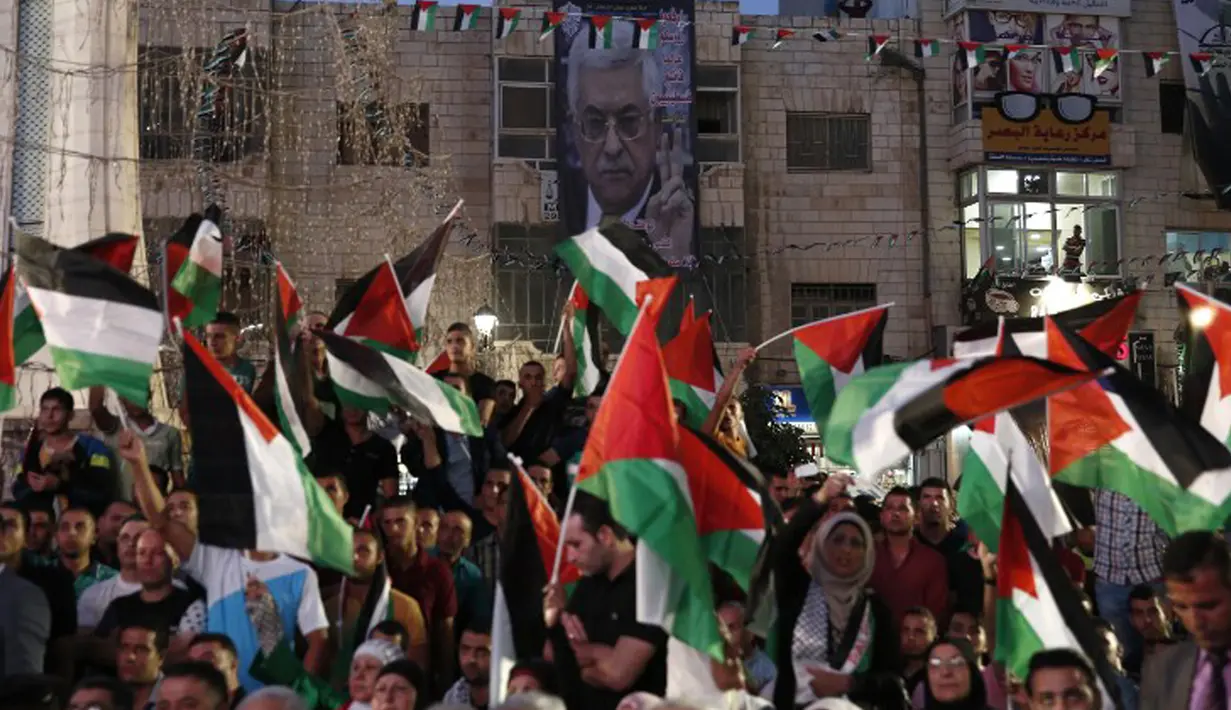 Warga Palestina melambaikan bendera nasional mereka saat menunggu live-screening pidato Presiden Mahmud Abbas sebelum pengibaran bendera Palestina di markas besar PPB di New York, Rabu (30/9/2015). (AFP PHOTO/ABBAS Momani)