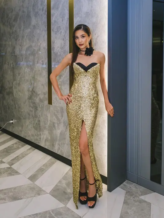 Penampilan megah nan elegan Mikha Tambayong dibalut gaun emas. Strapless dress ini membalut tubuhnya dengan sangat baik, memiliki detail high-slit, dengan sentuhan open-toe pumps dan choker berbentuk bunga mawar hitam untuk menambah kesan mewah. Foto: Instagram.