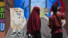 Seorang seniman menyelesaikan lukisan mural Pemilu 2019 di Banda Aceh, provinsi Aceh (17/3). Indonesia akan mengadakan pemilihan presiden dan parlemen secara serentak pada 17 April. (AFP Photo/Chaideer Mahyuddin)