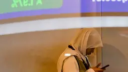 Seorang wanita terlihat di balik monitor kaca yang menampilkan Indeks Harga Saham Gabungan (IHSG), yang anjlok signifikan selama pembukaan pasar, di gedung Bursa Efek Indonesia di Jakarta pada Rabu 13 Mei 2026. (BAY ISMOYO/AFP)