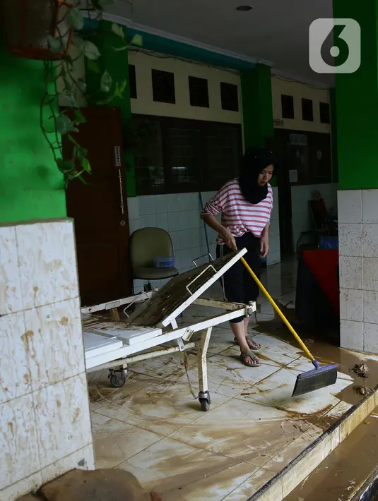 Murid SMA Negeri 8 Jakarta membersihkan lumpur sisa banjir di sekolahnya di Bukit Duri, Tebet, Sabtu (4/1/2020). Data Kemendikbud menyebutkan per 3 Januari 2020 terdapat 201 sekolah terendam banjir dan 89 sekolah mengalami gangguan pada akses menuju sekolah. (Liputan6.com/Herman Zakharia)