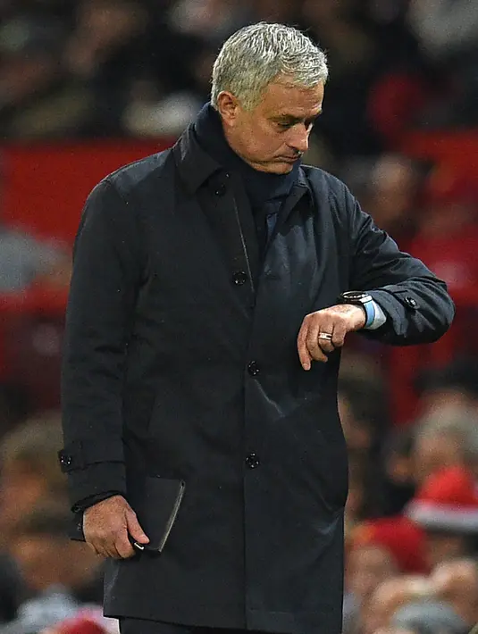 Pelatih Tottenham Hostpur, Jose Mourinho melihat jam tangannya saat pertandingan melawan Manchester United pada lanjutan Liga Inggris di Old Trafford, Rabu (4/12/2019). Mourinho gagal mengalahkan Manchester United mantan klub yang pernah dilatihnya. (AFP Photo/Oli Scarff)