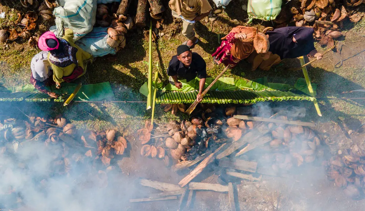 Pemandangan dari udara menunjukkan para peserta memasak lemang, hidangan nasi ketan tradisional yang dimasukkan ke dalam tabung bambu dan diisi dengan santan yang kemudian diletakkan di atas api, selama acara memasak massal di Blang Pidie, Kabupaten Aceh Barat Daya, Aceh, pada Sabtu 25 April 2026. (CHAIDEER MAHYUDDIN/AFP)