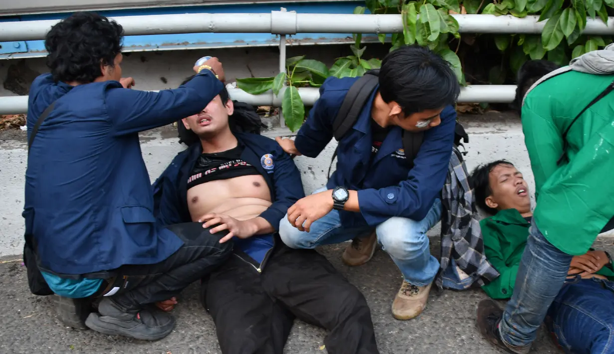 Sejumlah mahasiswa merawat rekan mereka yang terluka saat demonstrasi menolak pengesahan RUU KUHP dan revisi UU KPK di depan Gedung DPR, Jakarta, Selasa (24/9/2019). Sejumlah mahasiswa tumbang setelah polisi menembakkan gas air mata untuk membubarkan demonstrasi. (ADEK BERRY/AFP)