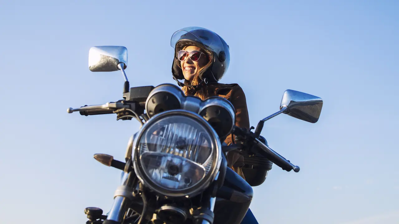 Pengendara motor wanita memakai helm dan mengendarai sepeda motor