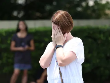 Seorang wanita menutup wajahnya pasca teror penembakan di Pulse, klub malam khusus kaum gay di kota Orlando, Florida, AS, Minggu (12/6). 50 orang tewas dan 53 terluka akibat penembakan yang dilakukan oleh Omar Saddiqui Mateen. (Gregg NEWTON/AFP)