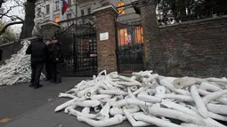 Petugas keamanan mengamati tumpukan lengan manekin di depan pintu masuk Kedutaan Besar (Kedubes) Rusia di London, Kamis (3/11). Pengunjuk rasa mengklaim lengan-lengan plastik itu mewakili luka-luka yang dialami warga Aleppo Suriah. (REUTERS/Toby Melville)