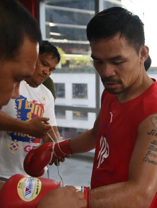 Petinju Filipina, Manny Pacquiao melepaskan sarung tinju usai berlatih di gym di Manila, (17/5). Pacquiao yang juga senator Filipina akan bertanding pada kelas welter dunianya melawan petinju Argentina Lucas Matthysse. (AFP Photo/Ted Aljibe)