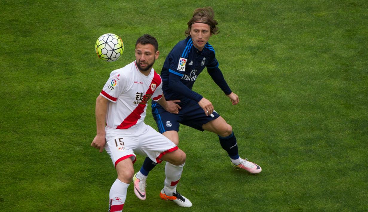 Pemain Real Madrid, Luka Modric, berebut bola dengan pemain Rayo Vallecano, Razvan Rat, dalam laga La Liga Spanyol di Stadion Campo de Fútbol de Vallecas, Sabtu (23/4/2016). (AFP/Curto De La Torre)