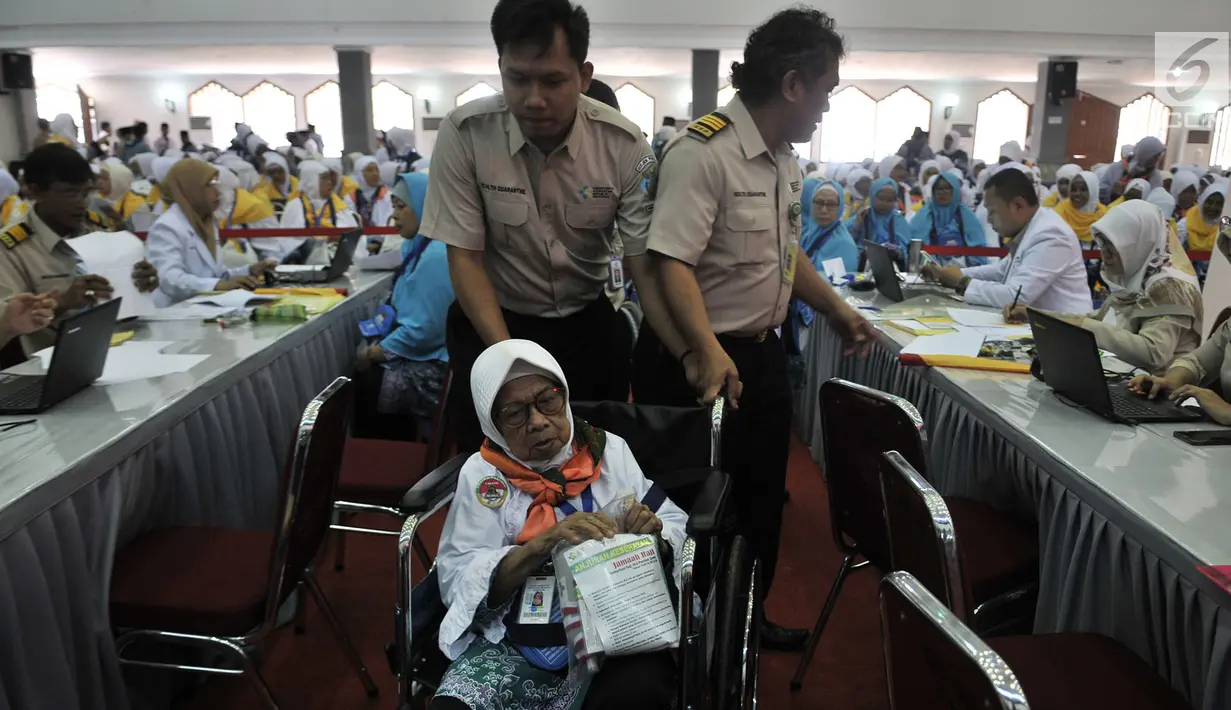 Petugas menuntun salah seorang calon jemaah haji lansia saat menjalani tes kesehatan di Asrama Haji Pondok Gede, Jakarta, Senin (16/7). Sebanyak 388 calon jemaah haji asal Jakarta Timur telah mulai masuk ke asrama. (Merdeka.com/Iqbal Nugroho)