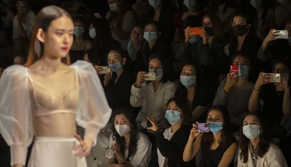 Para peserta mengenakan masker wajah untuk melindungi diri dari COVID-19 saat menonton model menampilkan kreasi perancang busana dari Finelycup dalam China Fashion Week di Beijing, China, Selasa (7/9/2021). (AP Photo/Mark Schiefelbein)