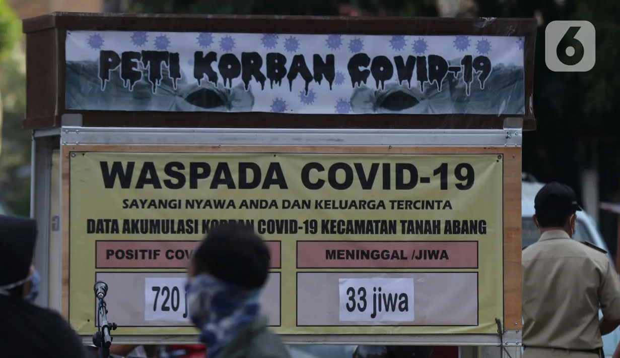 Warga melintasi tanda peringatan bahaya COVID-19 di sekitar Pasar Blok A Tanah Abang, Jakarta, Selasa (1/9/2020). Guna meningkatkan kewaspadaan masyarakat, muspida kecamatan Tanah Abang memajang peti mati dilengkapi data jumlah korban COVID-19 di wilayah tersebut. (Liputan6.comHelmi Fithriansyah)