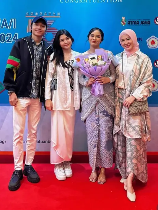 Okie memilih mengenakan outer batik panjang dipadukan inner kemeja putih dan kain motif daun warna pink dan hitam. Tampak ia pun membawa sling bag Gucci dan kitten stiletto heels putih. [@okieagustina_]