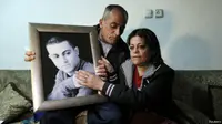 Ayah dan ibu Mohammed Musallam memegang foto putra mereka di kediaman pasangan warga Israel keturunan Arab itu. (BBC)