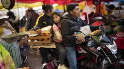 Sebuah keluarga membawa belanjaan dengan sepeda motor mereka di pasar makanan populer di Puno, Peru, Minggu (29/1/2023). Pergolakan politik telah memicu kemarahan dan terkadang protes keras di seluruh negara Andean, terutama di daerah pedesaan dan pertambangan. (AP Photo/Rodrigo Abd)