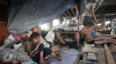Seorang anak terlihat belajar meski dengan kondisi tempat tinggal yang memperihatinkan, Jakarta, Jumat (16/9). Sebelumnya, 50 bangunan liar di bawah kolong Tol Sedyatmo, Penjaringan kembali ditertibkan Pemkot Jakut. (Liputan6.com/Yoppy Renato)