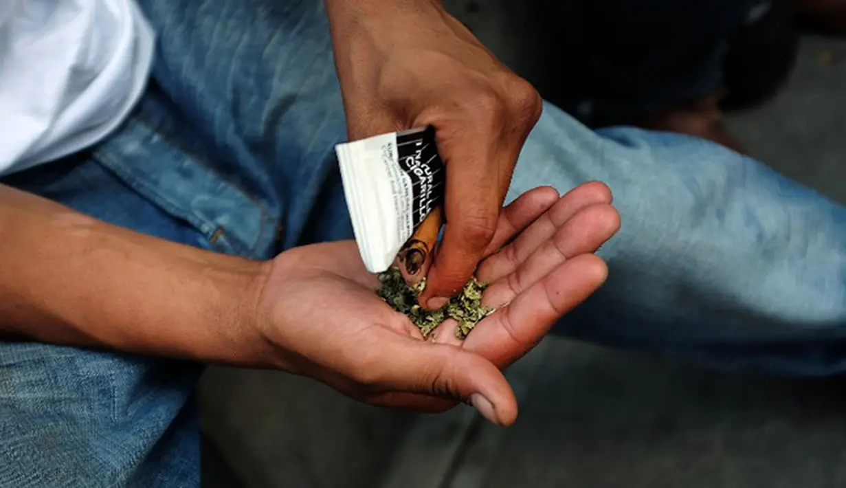Seorang pria menyiapkan ganja sintetis untuk dihisap di pinggir jalan East Harlem, New York (5/8/2015). Ganja sintetis merupakan zat psikoaktif yang dirancang untuk meniru atau menghasilkan efek yang mirip dengan ganja. (AFP PHOTO/SPENCER PLATT)