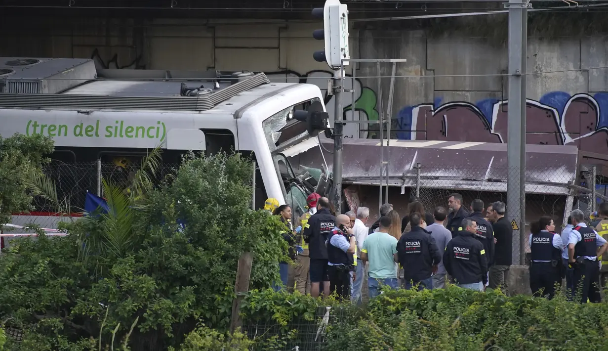 Polisi dan petugas penyelamat berdiri di dekat reruntuhan setelah kecelakaan kereta api di Sant Boi dekat Barcelona, Spanyol, Senin, 16 Mei 2022. Kereta barang menabrak bagian depan kereta penumpang yang sedang keluar dari stasiun. (AP Photo/Joan Mateu Para)