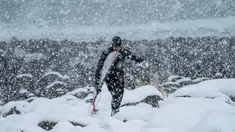 Seorang surfer atau peselancar berjalan keluar dari air di bawah hujan salju di Unstad, Norwegia Utara (11/3). Pria ini berselancar di wiliyah Lingkaran Arktik dengan suhu minus 13 derajat Celsius. (AFP Photo/Olivier Morin)