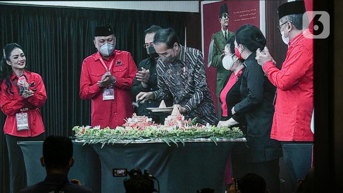 Presiden Joko Widodo atau Jokowi (tengah) memotong tumpeng disaksikan Ketua Umum PDIP Megawati Soekarnoputri (ketiga kanan) saat Rakernas II PDIP di Jakarta, Selasa (21/6/2022). Rakernas PDIP kali ini mengusung tema 'Desa Kuat, Indonesia Maju dan Berdaulat'. (Liputan6.com/Faizal Fanani)