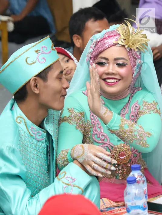 Pasangan nikah massal bercanda usai ijab kabul di jalan MH Thamrin, Jakarta, Senin (31/12). 557 pasangan mengikuti nikah massal dan isbat nikah pada malam pergantian tahun 2018-2019. (Liputan6.com/Helmi Fithriansyah)