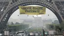 Sebuah spanduk bertuliskan "Kebebasan, Kesetaraan, Persaudaraan" terpampang di Menara Eiffel di Paris, Prancis, Kamis (5/5). (AFP/Jacques DEMARTHON)