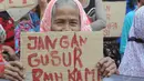 Seorang wanita lansia tampak membawa lembaran karton bertuliskan "jangan gusur rumah kami" di depan Balaikota DKI Jakarta, (11/9/14). (Liputan6.com/Herman Zakharia)