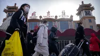 Para pemudik yang memakai masker berjalan melewati pintu masuk Stasiun Kereta Api Beijing di Beijing, China, Sabtu (14/1/2023). Jutaan warga China diperkirakan akan melakukan perjalanan selama periode liburan Tahun Baru Imlek tahun ini. (AP Photo/Mark Schiefelbein)