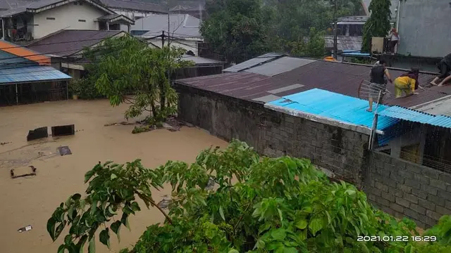 Sejumlah warga Manado memilih naik ke atap rumah karena volume air yang terus meningkat akibat banjir.