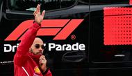 Pembalap Ferrari,  Lewis Hamilton, melambaikan tangan ke fans saat parade pembalap sebelum balapan F1 GP Inggris di Sirkuit Silverstone, Minggu (6/7/2025). (AFP/Ben Stansal)