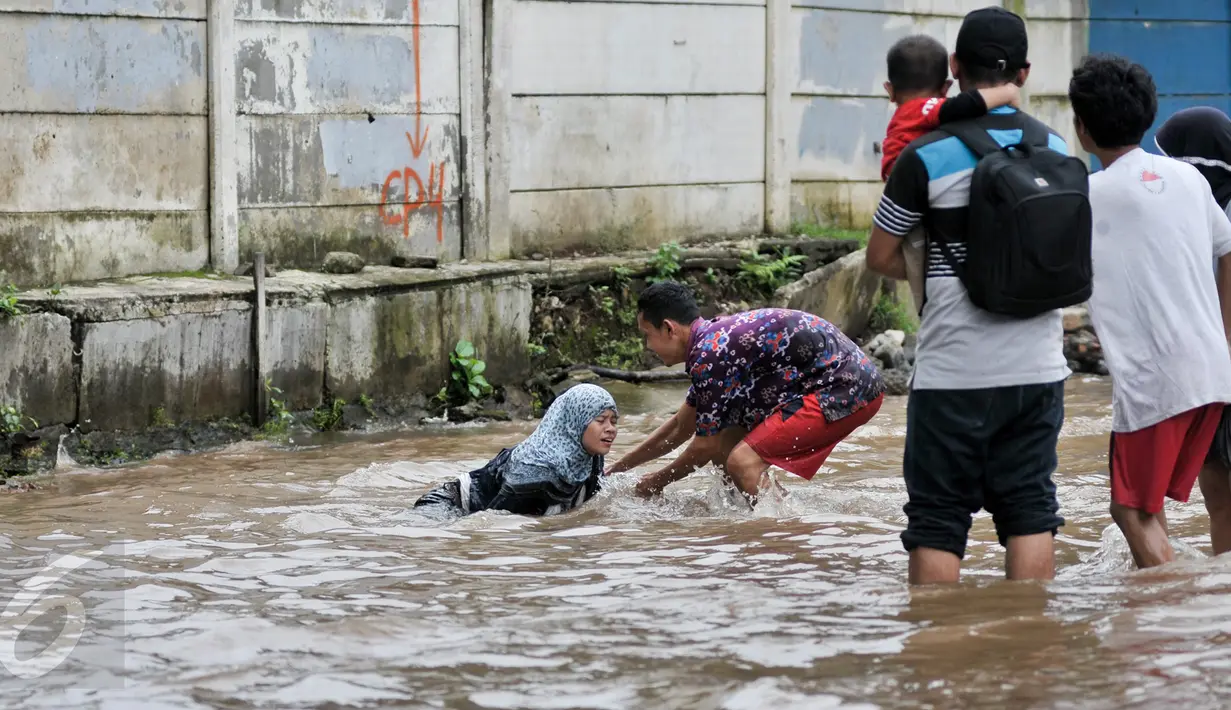 Seorang lelaki membantu membangunkan wanita yang terperosok ke dalam lubang saat banjir di kawasan Bukit Duri, Jakarta, Selasa (21/2). Salah satu bahaya banjir ialah tidak terlihatnya lubang yang bisa menyebabkan kecelakaan. (Liputan6.com/Yoppy Renato)